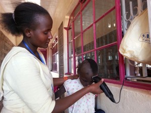 A girl being given a hair cut by the head teacher.